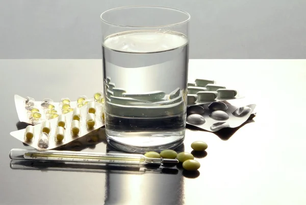 Glass of water and medicines for cure — Stock Photo, Image