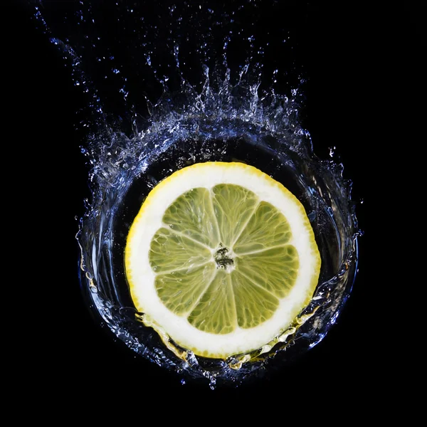 Fatia de limão caindo na água . — Fotografia de Stock