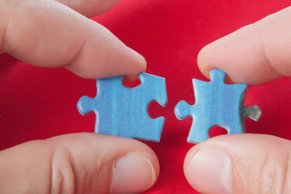 Conectando dos puzzles. sobre un fondo rojo. — Foto de Stock