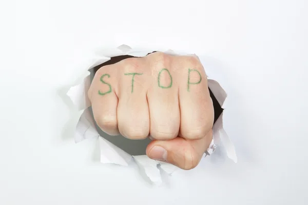 Fist of the hole in the paper that says stop. – stockfoto