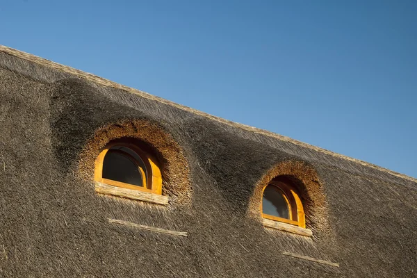 Små fönster i ett hus med vasstak — Stockfoto
