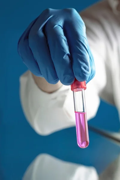 Teste de tubo com um líquido de rosa no fundo azul — Fotografia de Stock