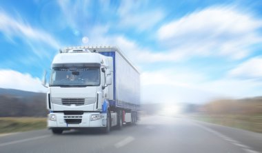 Truck on blurry road over blue cloudy sky background clipart