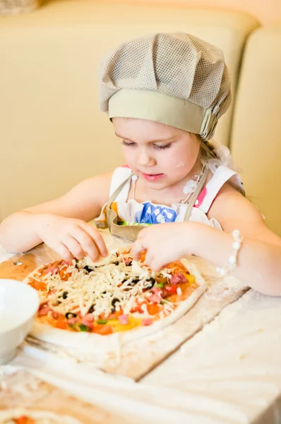 Little girl adding cheese in pizza — Stock Photo, Image