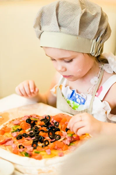 Little girl adding ingredients in pizza — Stock Photo, Image