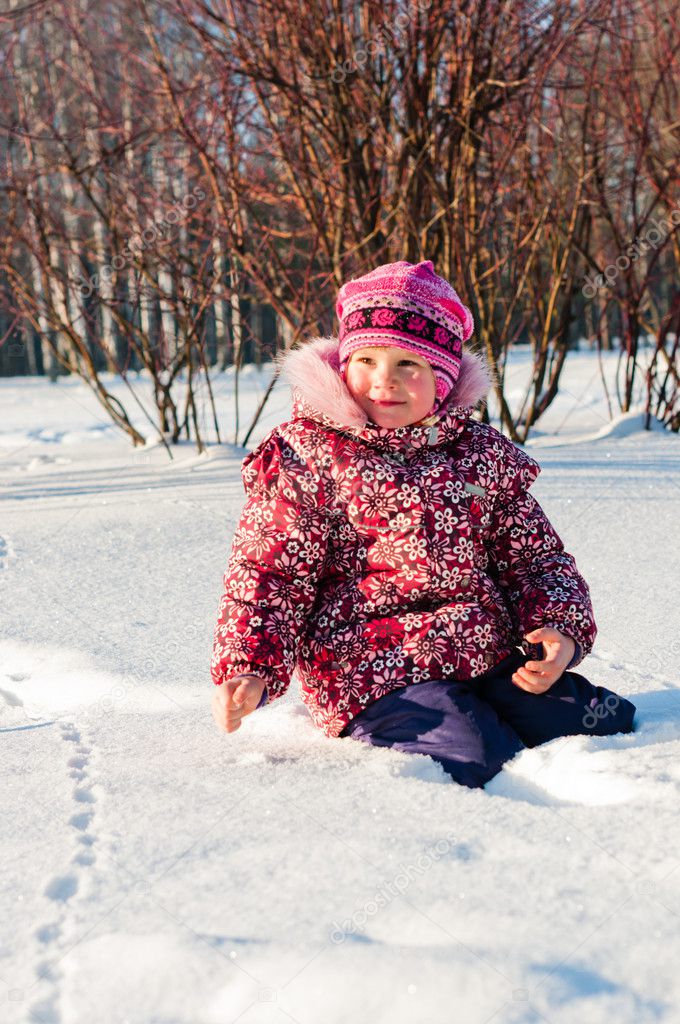 Baby sits on snow and looks