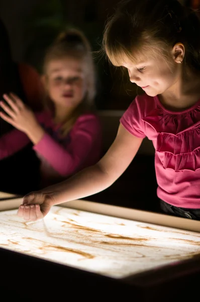 Девушка льет песок на стол — стоковое фото