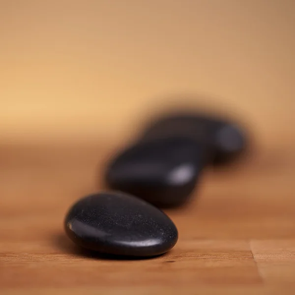 stock image Black stones on wood background