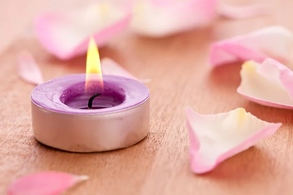 Rose bladeren met candel op houten achtergrond — Stockfoto