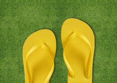 Yeşil çimenlerin üzerinde sarı flip flop