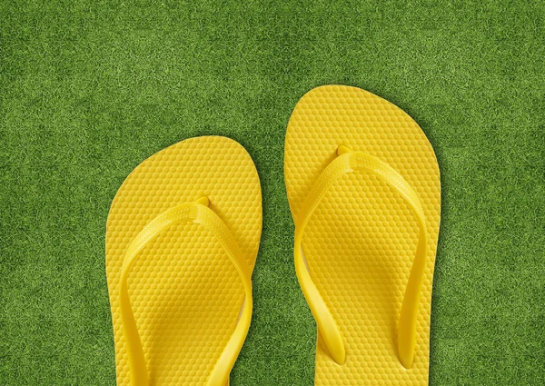 Chinelos amarelos na grama verde — Fotografia de Stock