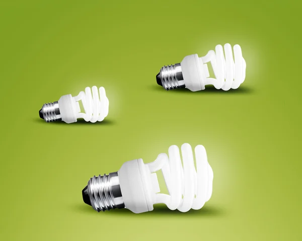 Trzy świecące światła żarówki pomysł na zielonym tle — Zdjęcie stockowe