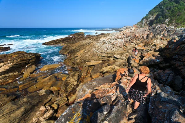 Mulheres caminhando ao longo da costa rochosa — Fotografia de Stock