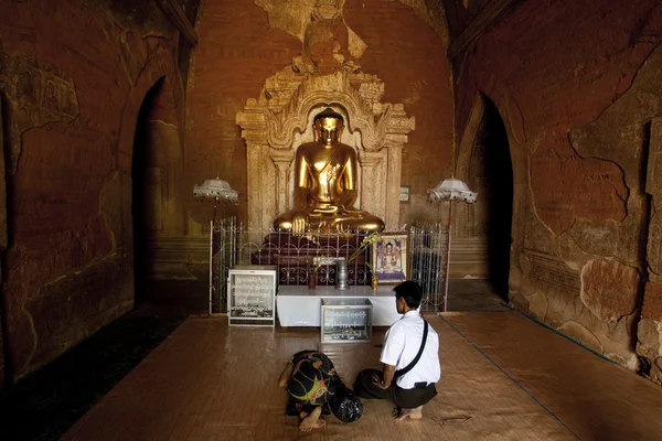 Orando em frente à estátua de buda dourada no templo de Htilominlo Pahto — Fotografia de Stock
