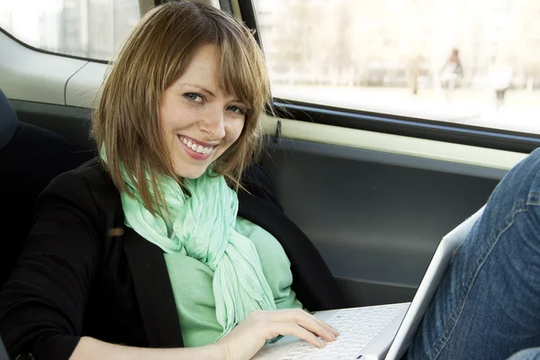 Młoda kobieta korzysta z laptopa w samochodzie — Zdjęcie stockowe