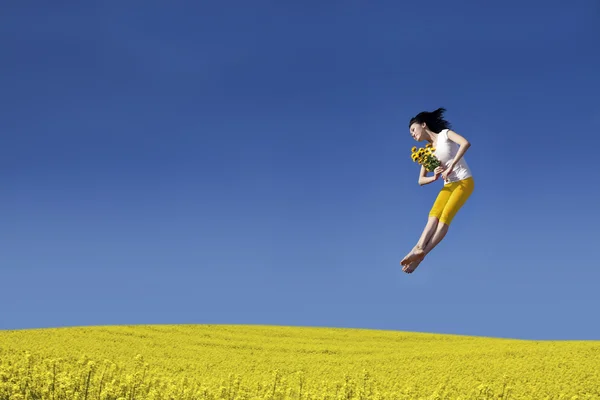 Happy Woman jumping with flower — Stock Photo, Image
