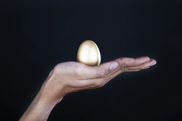 Mano con huevo de oro — Foto de Stock