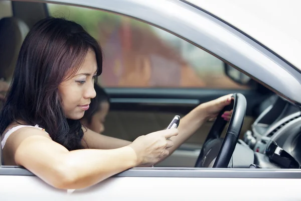 Женщина за рулем с помощью мобильного телефона — стоковое фото