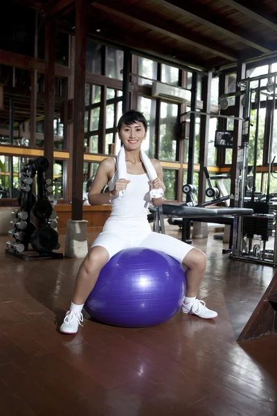 Азиатка позирует со швейцарским мячом в спортзале — стоковое фото