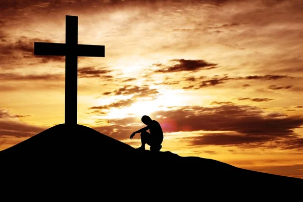 Чоловік сидить відчайдушно під хрестом Стокове Зображення