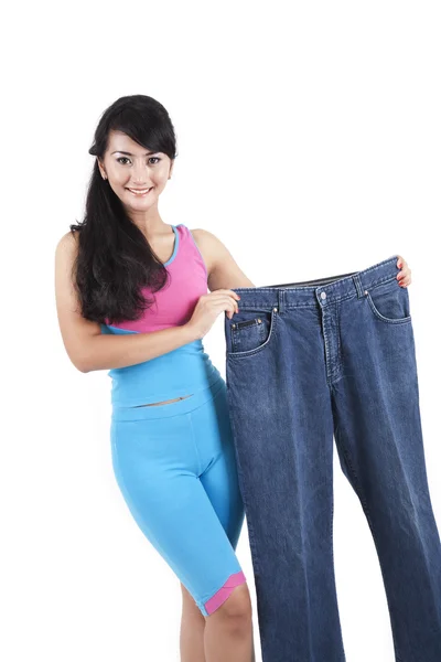 Fitness woman shows her an old jeans — Stock Photo, Image