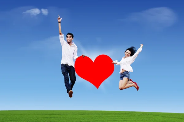 Couple jumping on the sky with heart — Zdjęcie stockowe
