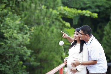 Happy pregnant couple looking at nature clipart