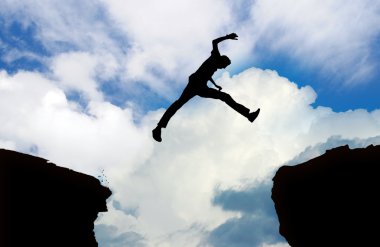 Silhouette of man jumping cliff 2 clipart