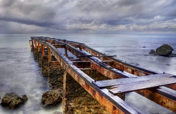 Bulutlu bir günde eski paslı pier — Stok fotoğraf