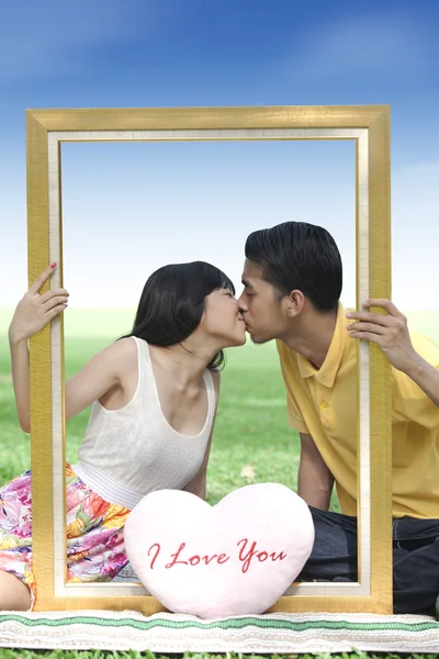 Jeune couple embrasser avec un cadre — Photo