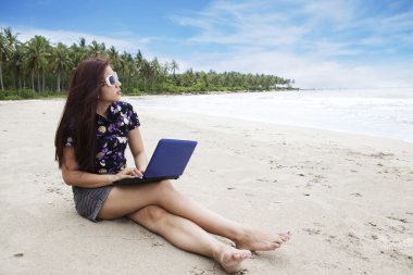 Casual businesswoman working on the beach clipart