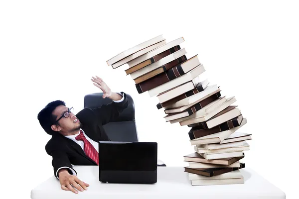 Scared businessman with pile of books Stock Photo