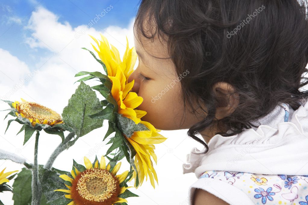 Cute girl smelling sunflowers