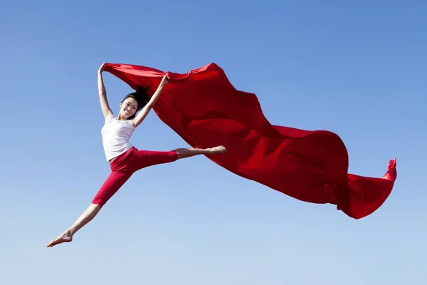 Jovem mulher atraente pulando com cachecol vermelho — Fotografia de Stock