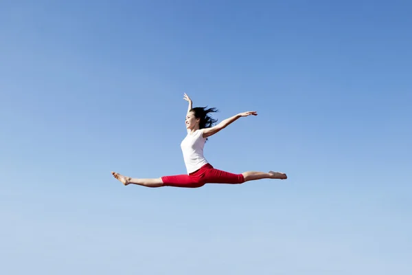 Азиатка, прыгающая через голубое небо — стоковое фото