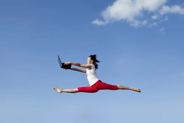 Beautiful woman jumps with laptop — Stock Photo, Image