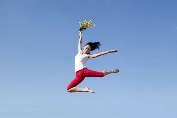 Joven mujer asiática salta con flores — Foto de Stock