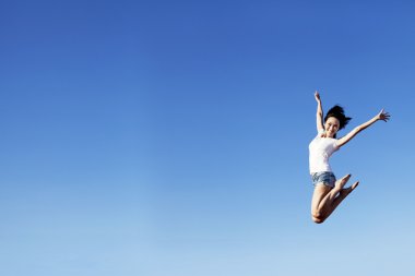 Joyful woman jumping over clear blue sky clipart