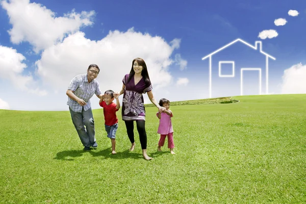 Giovane famiglia asiatica con una casa disegnata sul campo — Foto Stock