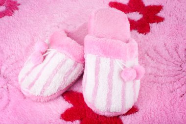 Pink home slippers on fluffy bath rug clipart