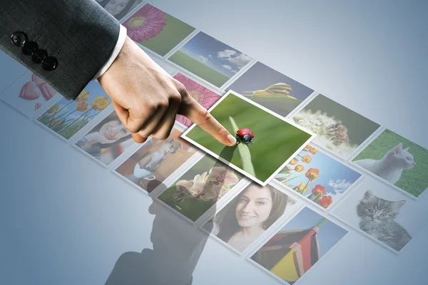 Touchscreen interface: man hand reaching images on the screen — Stock Photo, Image