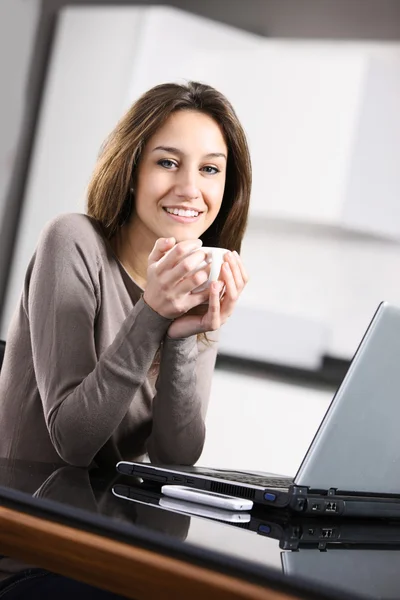 Νεαρή γυναίκα με ένα φλιτζάνι καφέ και το lap-top — Φωτογραφία Αρχείου