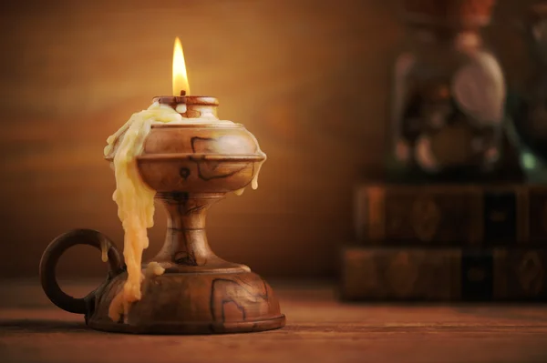 Vecchia candela su un tavolo di legno, vecchi libri sullo sfondo — Foto Stock