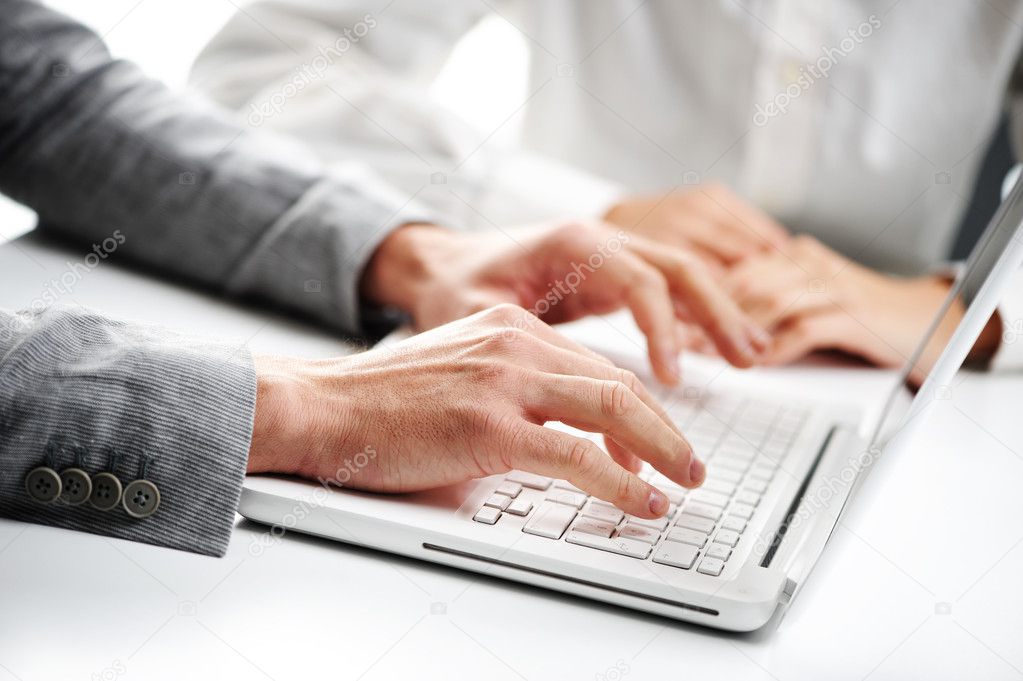 Businessman typing on a white computer keyboard, woman on backgr