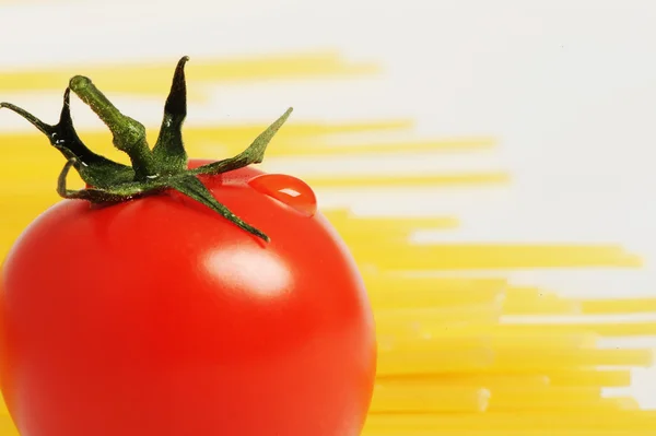 Pomidor z kropli i spaghetti niegotowane noodleson tło — Zdjęcie stockowe