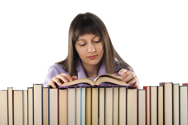 Jovem mulher lendo um livro atrás de uma grande pilha de livros — Fotografia de Stock