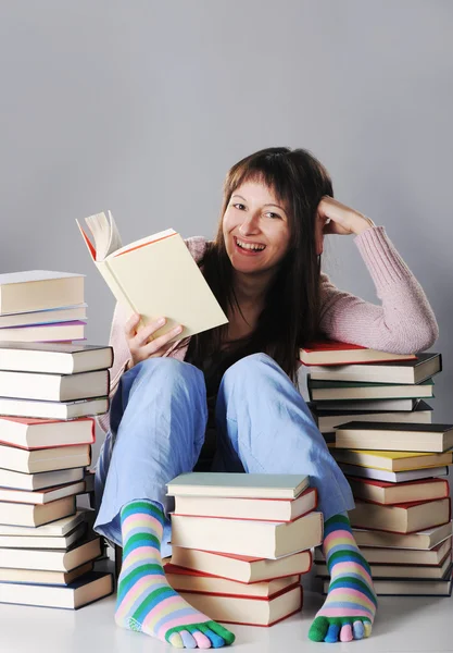 Ragazza carina che studia con una grande pila di libri — Foto Stock