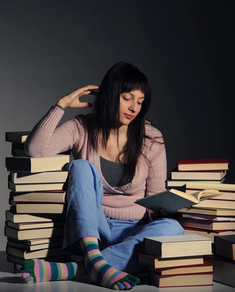 Ragazza carina che studia con una grande pila di libri — Foto Stock