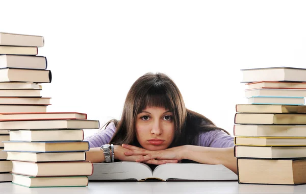 Устав от учебы, молодая женщина сидит на столе с книгами — стоковое фото
