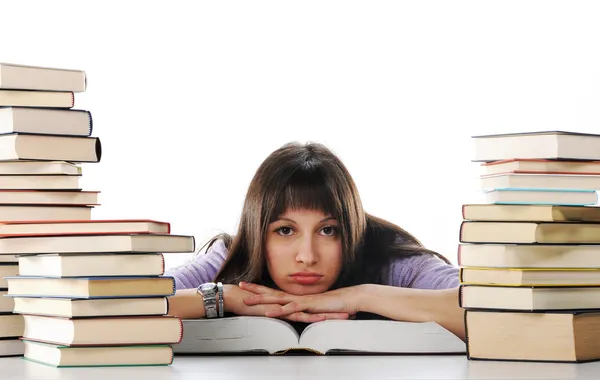 Studienmüde sitzt junge Frau mit Büchern auf ihrem Schreibtisch lizenzfreie Stockbilder